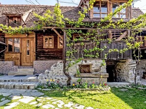 Ein rustikales Holzhaus mit Steinuntergrund, einer Holzveranda und einem Blumengarten.