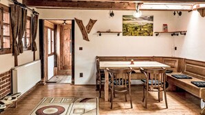 Un interior rústico con un banco de madera, una mesa y un cuadro en la pared.