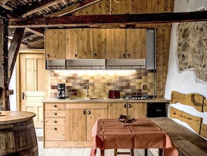Une cuisine rustique avec des meubles en bois, un pare-feu en pierre et une cuisinière à gaz.