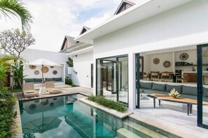 Uma casa moderna com piscina, área de estar externa e espaço para refeições.