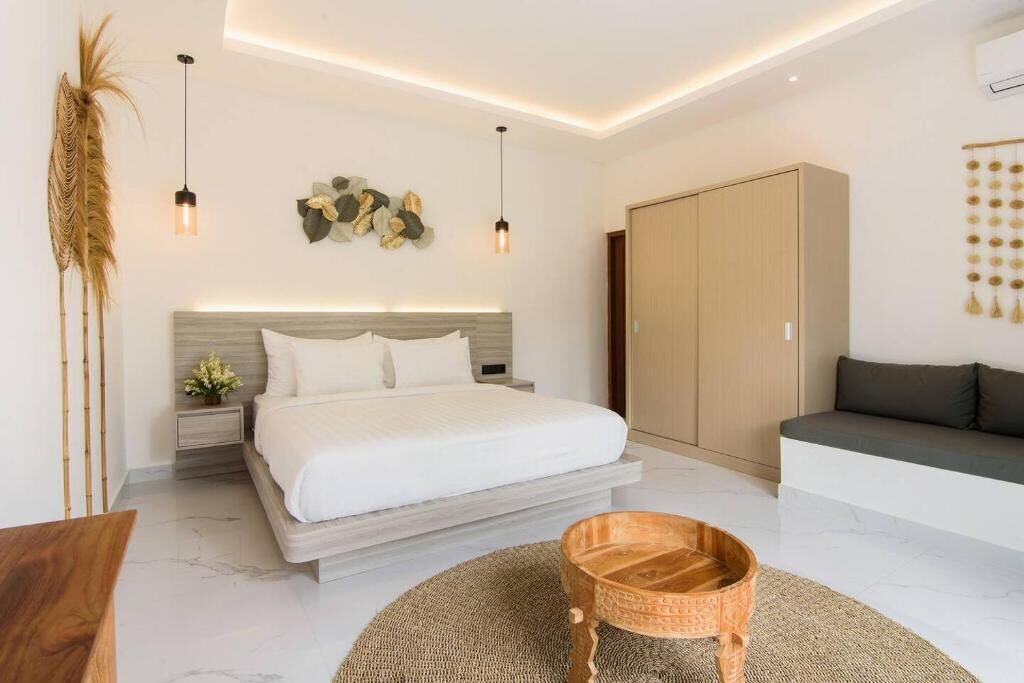 A modern bedroom with a bed, bedside tables, a wooden wardrobe, and a seating area with a sofa.