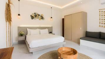 Une chambre moderne comprenant un lit, des tables de chevet, une armoire en bois et un coin salon avec un canapé.