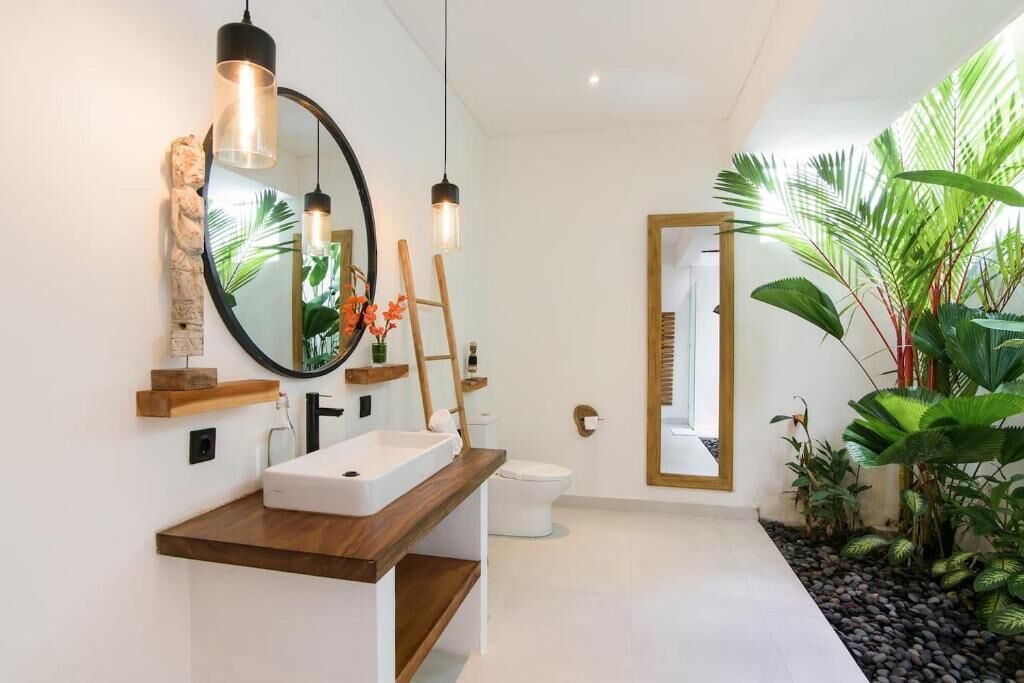 Ein modernes Badezimmer mit einem Holzkosmetikschrank, einem runden Spiegel und einer Toilette.