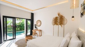 Een moderne slaapkamer met een groot bed, een bureau en uitzicht op een zwembad.