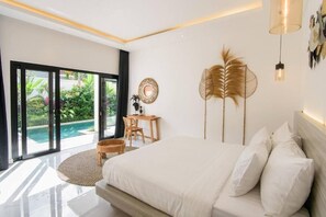 A modern bedroom with a large bed, a desk, and a view of a swimming pool. - Lena Villa by Tasvan (Badung)