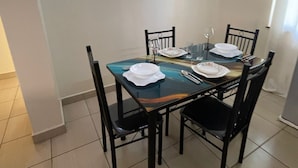 A dining area with a rectangular table, four chairs, and a wall-mounted mirror. - Pristine & Breezy 2BR Retreat with Pool, Gym & Balcony Views – Mtwapa Coast (Mtwapa)