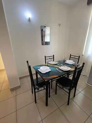 Uma área de refeições com uma mesa retangular, quatro cadeiras e um espelho fixado na parede.