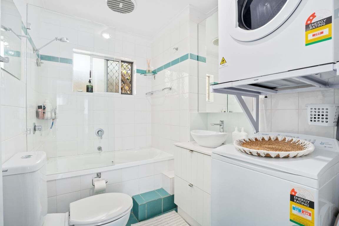 Une salle de bain moderne  équipée d’une baignoire, de toilettes et d’un lave-linge.