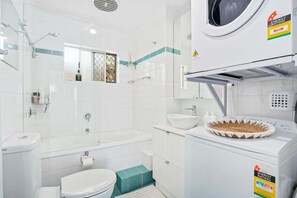 Ein modernes Badezimmer mit Badewanne, Toilette und Waschmaschine.