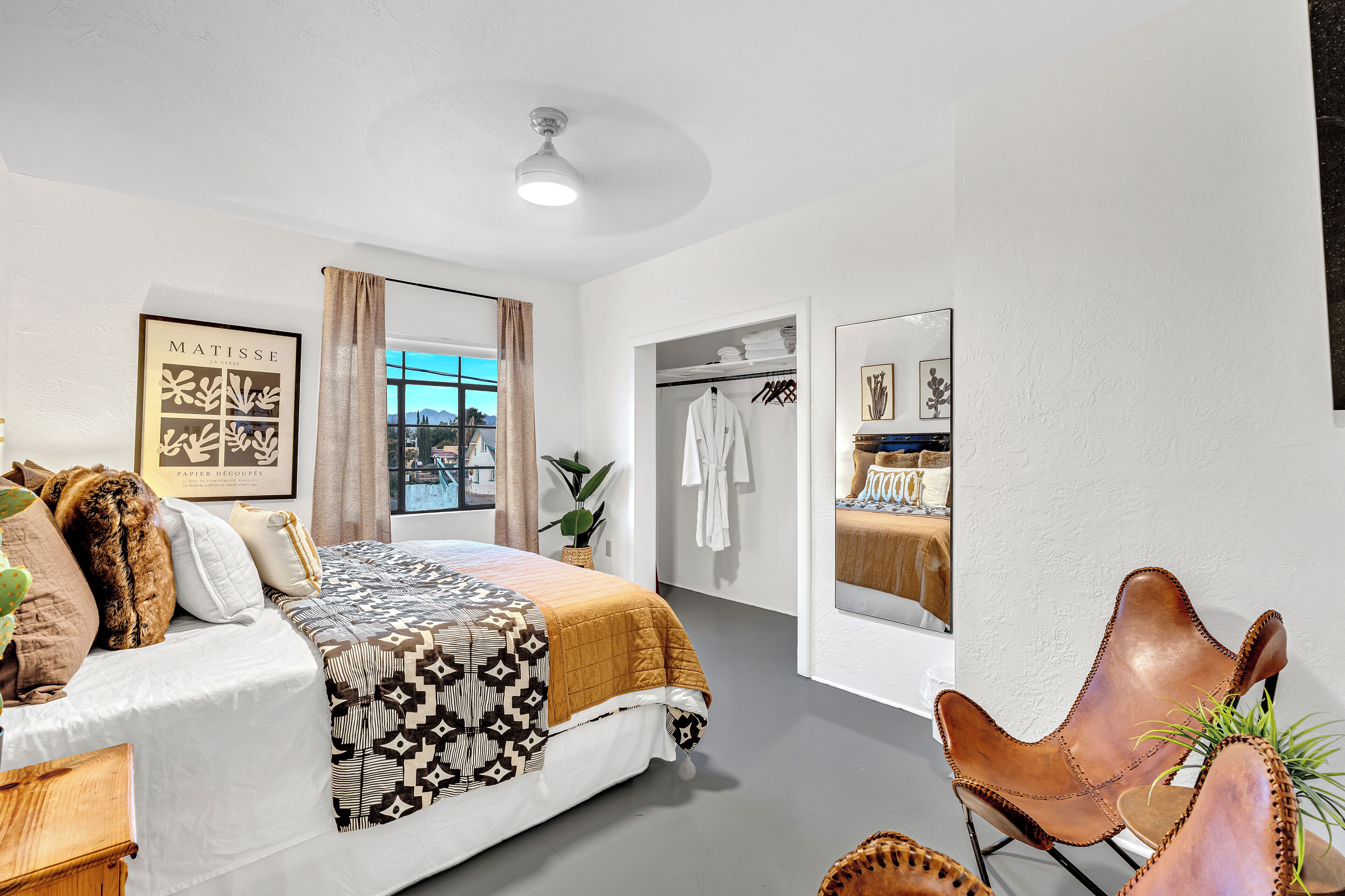A modern bedroom with a bed, a chair, a wardrobe, and a window with a view.
