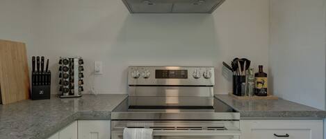 A kitchen with a stainless steel range hood, a knife block, and a bottle of liquor on the counter.