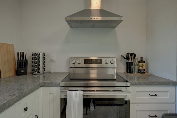 A kitchen with a stainless steel range hood, a knife block, and a bottle of liquor on the counter.