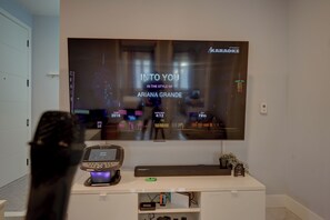 A television displaying a music video with the title 'INTO YOU' and the artist 'ARIANA GRANDE'.
