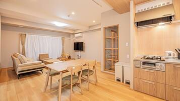 A compact living space with a kitchenette, a dining area, and a seating area with a sofa and chairs.