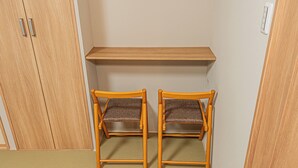 Una stanza con due sedie di legno, uno scaffale e un armadio.
