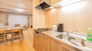 A compact kitchen with wooden cabinets, a gas stove, a coffee maker, and a sink.