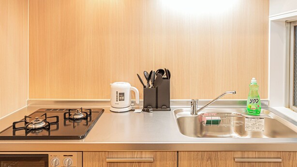 Una cucina moderna con piano cottura a gas, bollitore elettrico, lavello e una finestra.