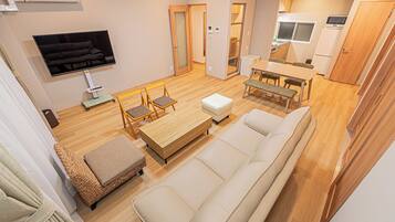A modern living room with a sofa, a coffee table, and a TV mounted on the wall.