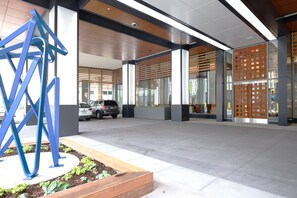 A modern building entrance with a parking area, a blue abstract sculpture, and a wooden slatted wall. - Blueground | Pentagon City, pool, nr Arlington Cemetery (Arlington)