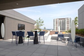 A rooftop patio with outdoor seating, a large white sculpture, and a view of high-rise buildings. - Blueground | Pentagon City, pool, nr Arlington Cemetery (Arlington)