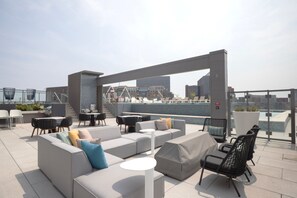 A rooftop terrace with a modern seating area, including sofas and chairs, and a view of the cityscape. - Blueground | Pentagon City, pool, nr Arlington Cemetery (Arlington)