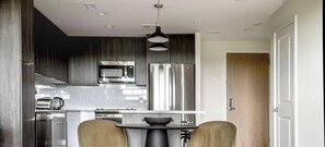 A modern kitchen with stainless steel appliances, a dining table with chairs, and a pendant light. - Blueground | Pentagon City, pool, nr Arlington Cemetery (Arlington)