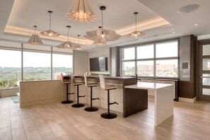 A modern kitchen with a central island, bar stools, pendant lighting, and large windows offering a city view. - Blueground | Pentagon City, pool, nr Arlington Cemetery (Arlington)