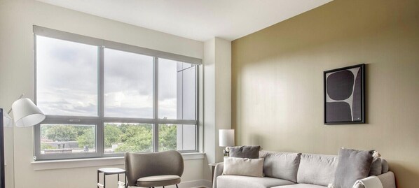 A room with a large window, a sofa, a chair, and a lamp. - Blueground | Pentagon City, pool, nr Arlington Cemetery (Arlington)