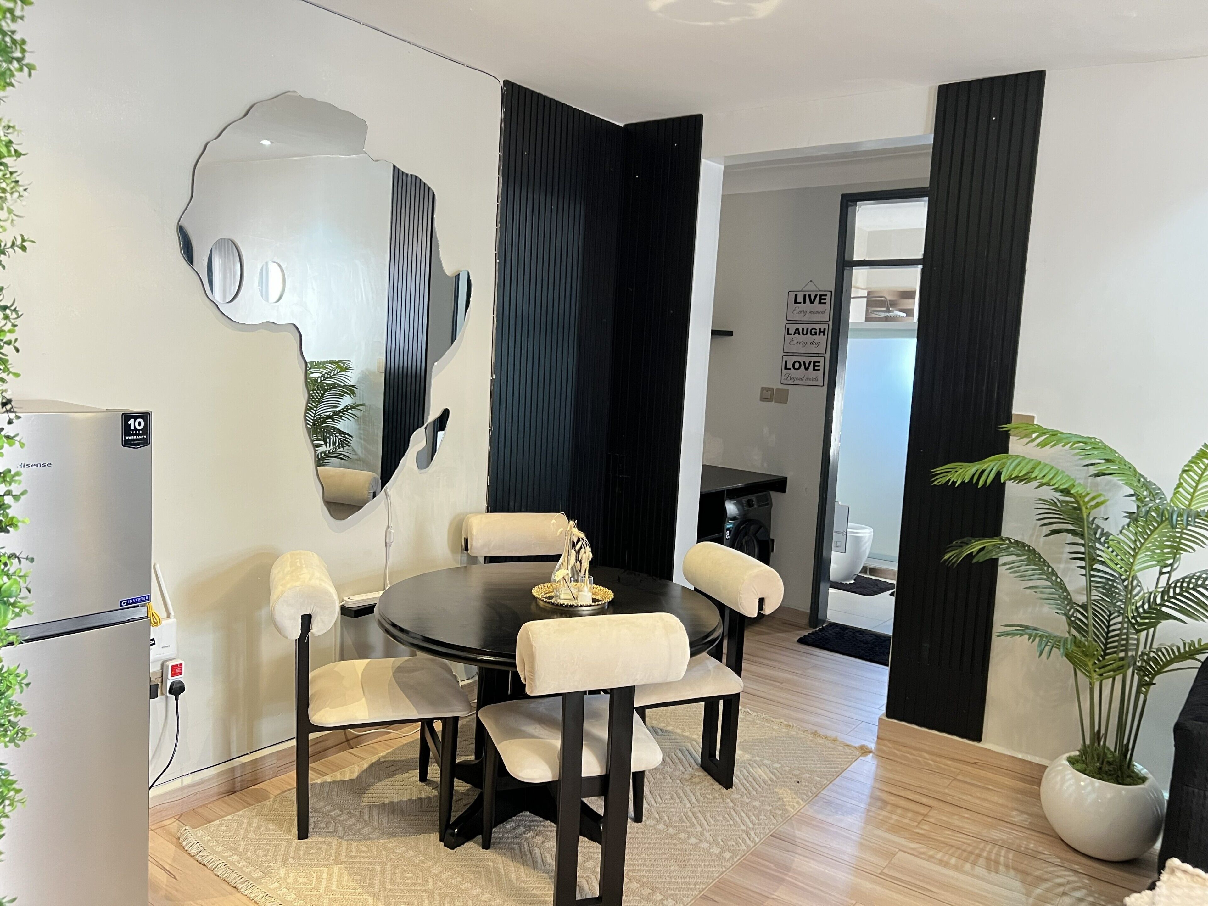 A modern dining area with a round table, six chairs, and a unique wall art piece.