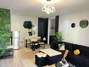 Ein modernes Wohnzimmer mit einer schwarzen Couch, einem runden Couchtisch und einem Essbereich mit schwarzem Tisch und Stühlen.