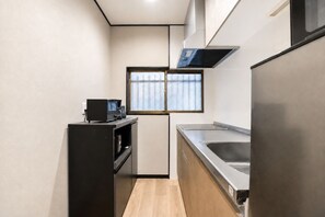 A compact kitchen with a refrigerator, a sink, a coffee machine, and a window with blinds. - Nishikujo -EN- (Osaka konohanaku nishikujyo)
