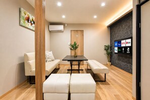 A modern meeting room with a wooden table, two sofas, a bench, and a wall-mounted TV displaying various streaming services. - Nishikujo -EN- (Osaka konohanaku nishikujyo)