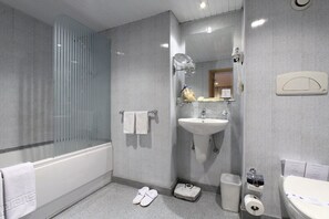 Et moderne badeværelse med badekar, vask, spejl og toilet.