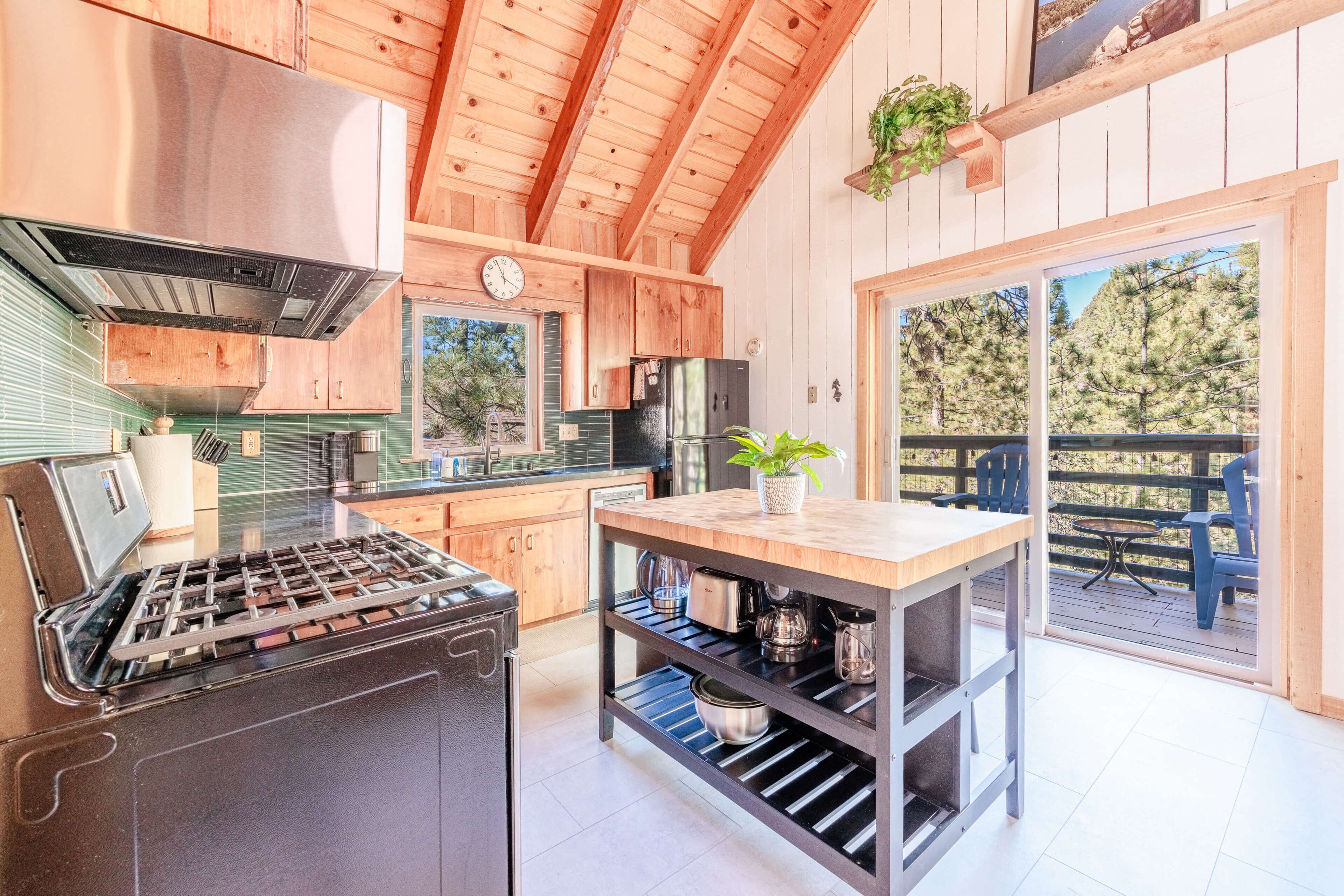 A modern kitchen with wooden cabinetry, a stainless steel stove, and a dining area with a table and chairs.