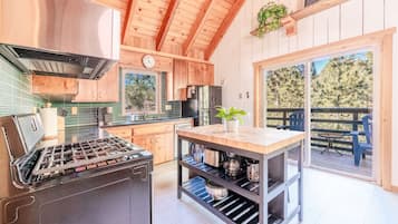 A modern kitchen with wooden cabinetry, a stainless steel stove, and a dining area with a table and chairs.