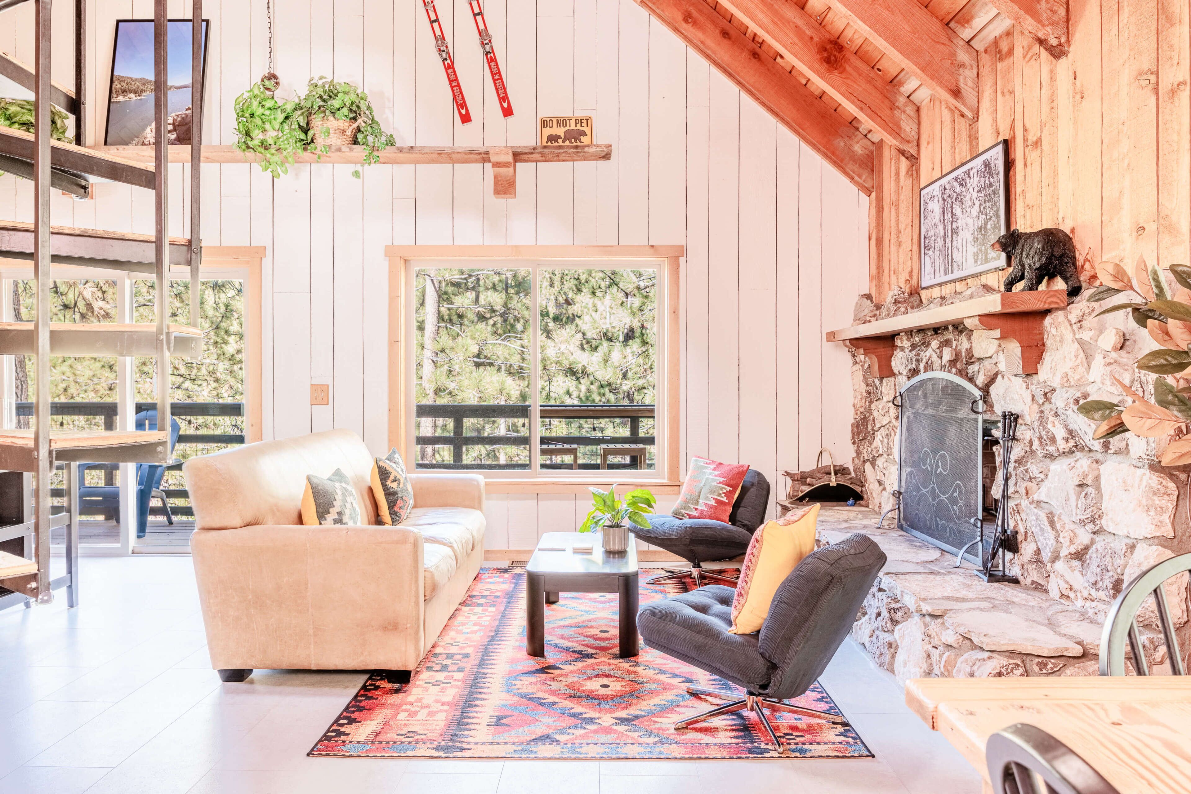 A cozy living room with a fireplace, a large window, and a stone wall.
