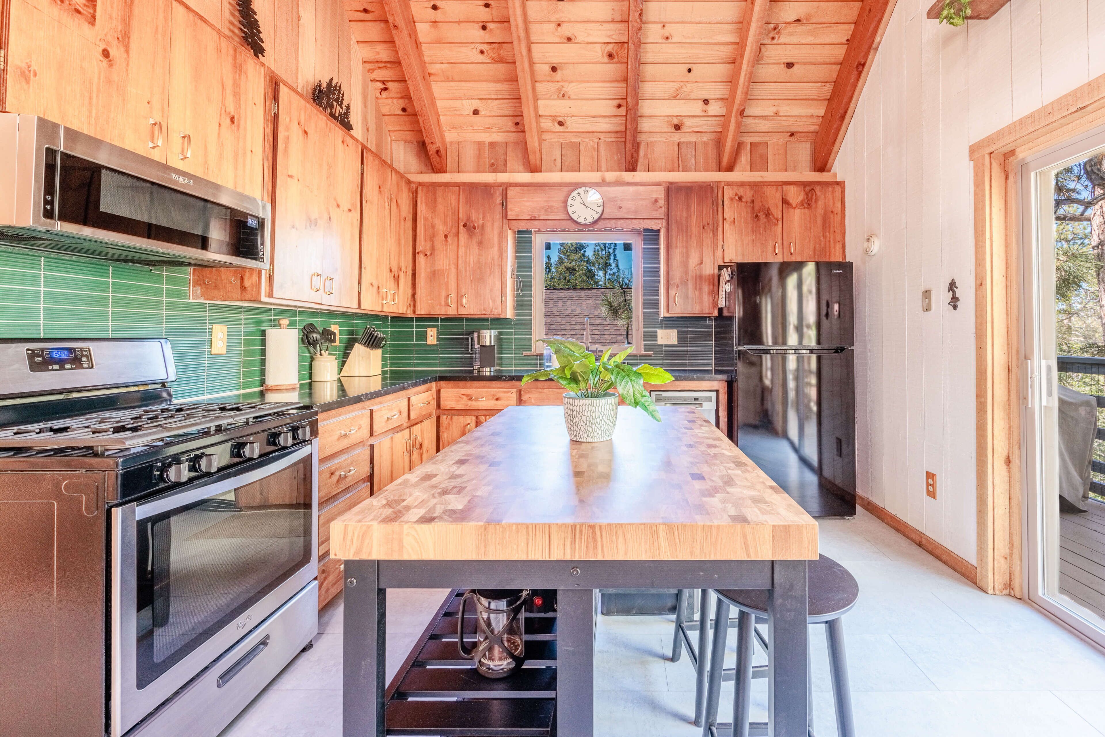 Cocina moderna con armarios de madera, una isla central, electrodomésticos de acero inoxidable y vistas al exterior.