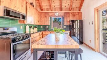 Cocina moderna con armarios de madera, una isla central, electrodomésticos de acero inoxidable y vistas al exterior.