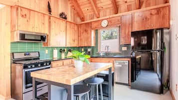 A kitchen with wooden cabinets, a stove, a refrigerator, and a clock on the wall.