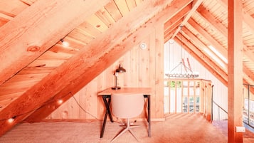 Une chambre mansardée avec un bureau, une chaise et un luminaire suspendu.