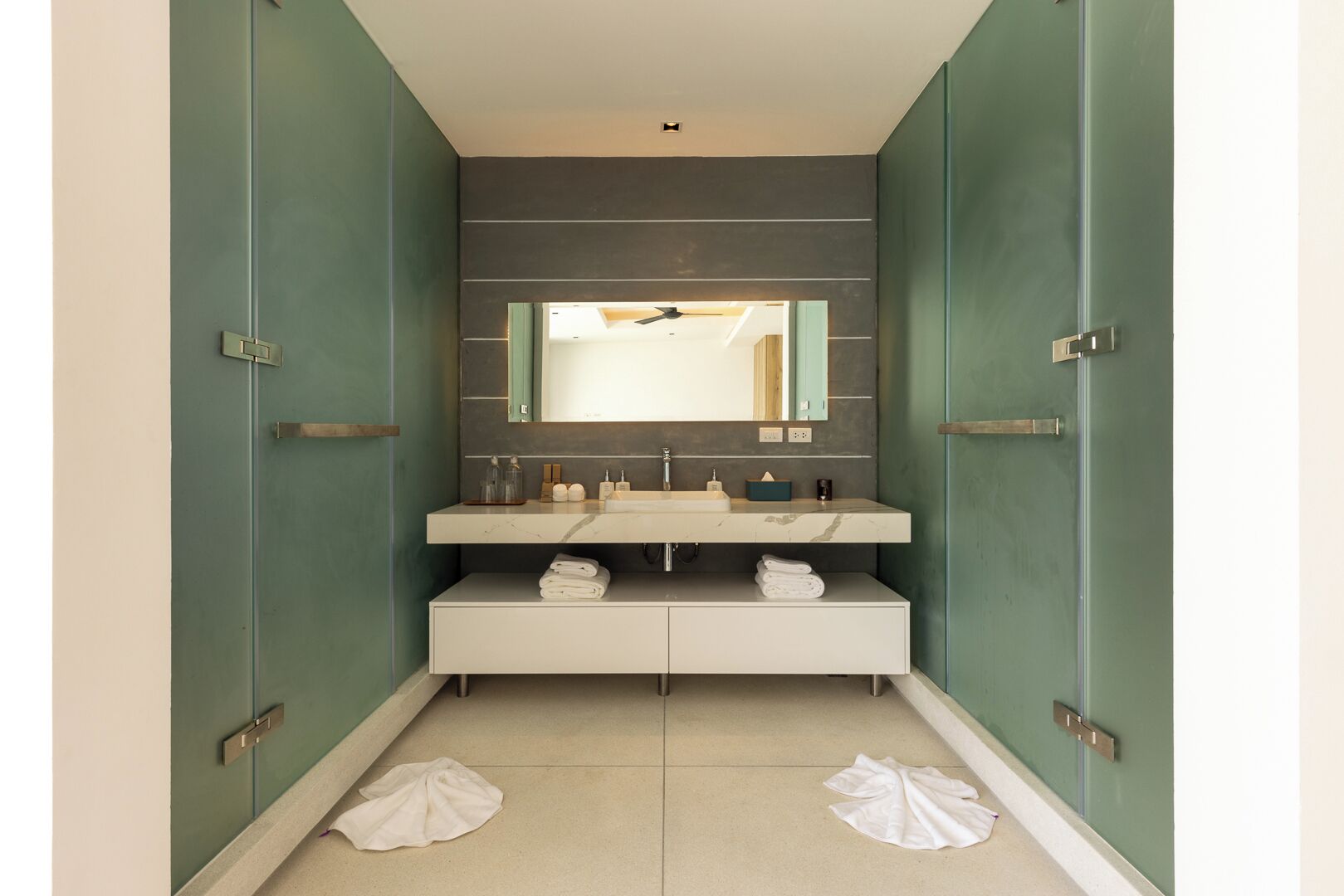 A bathroom with a vanity, mirror, and towel storage.