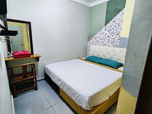 Un dormitorio con una cama, un espejo, un taburete de madera y una pared con un estampado colorido.