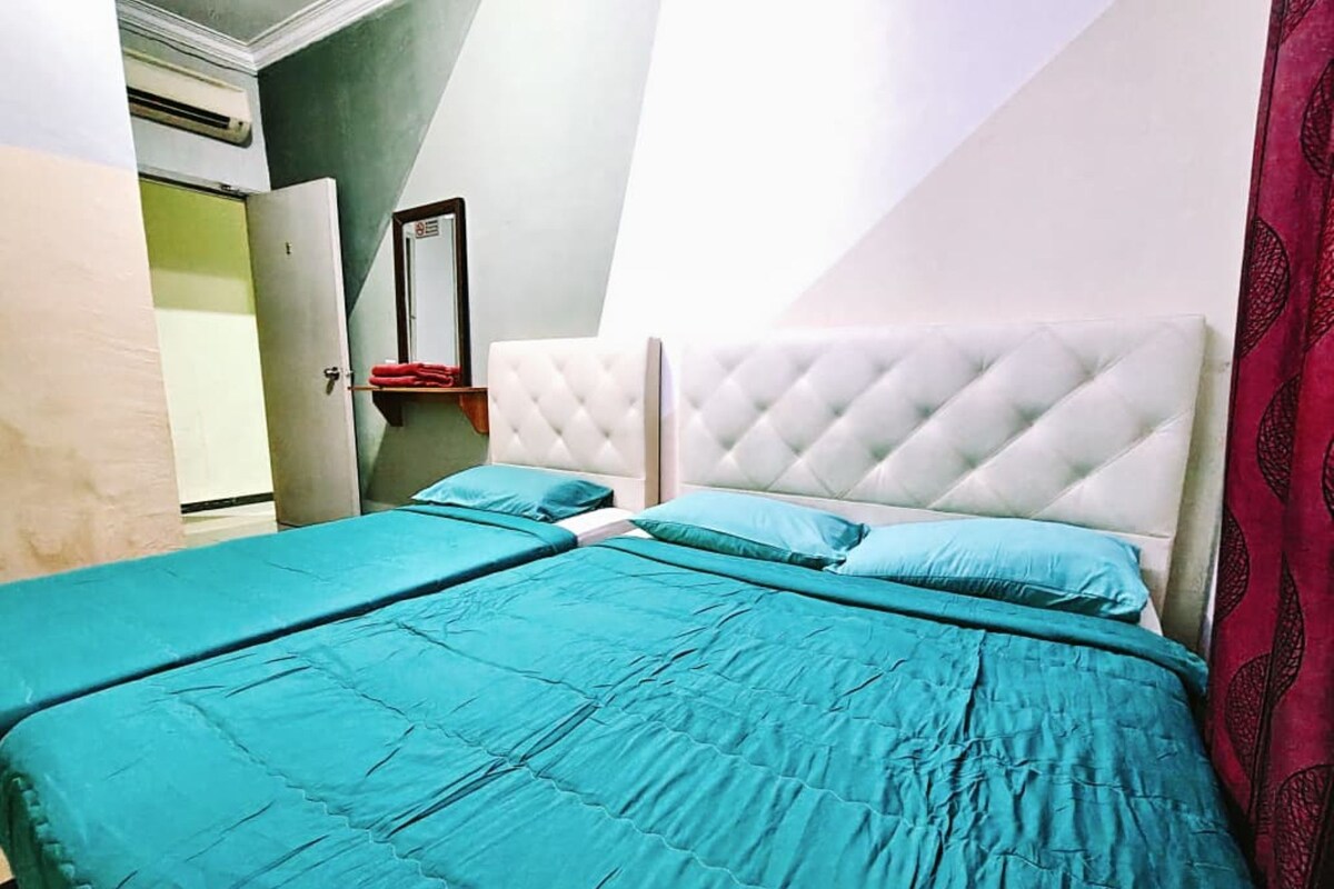 Ein Schlafzimmer mit zwei Betten, jeweils mit einer gesteppten Kopfteil, und einem roten Vorhang auf der rechten Seite.