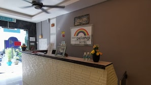 Un mostrador de recepción de hotel con un cartel que dice 'SERI PELANGI HOTEL' y un letrero que indica 'KELUAR', salida.