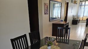 Un comedor con una mesa rectangular, sillas negras, una pequeña planta en maceta y un mantel decorativo.