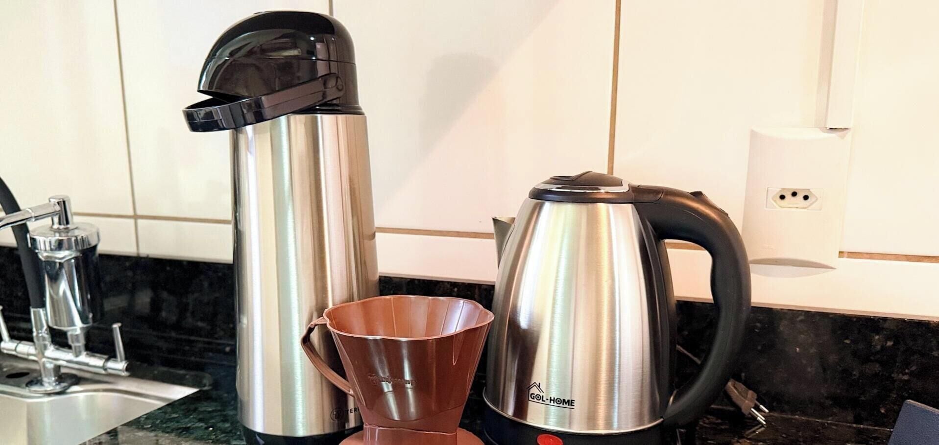 A kitchen with stainless steel appliances, including a coffee maker and a kettle.