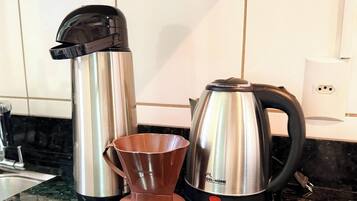A kitchen with stainless steel appliances, including a coffee maker and a kettle.