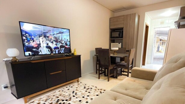 A living room with a television, a sofa, a dining table with chairs, and a kitchen area. - ASA Verona Park 06 2 Bedrooms Single Story House Timbo (Timbo)
