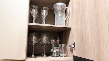 A wooden cabinet with shelves holding various glassware, including wine glasses and a pitcher.