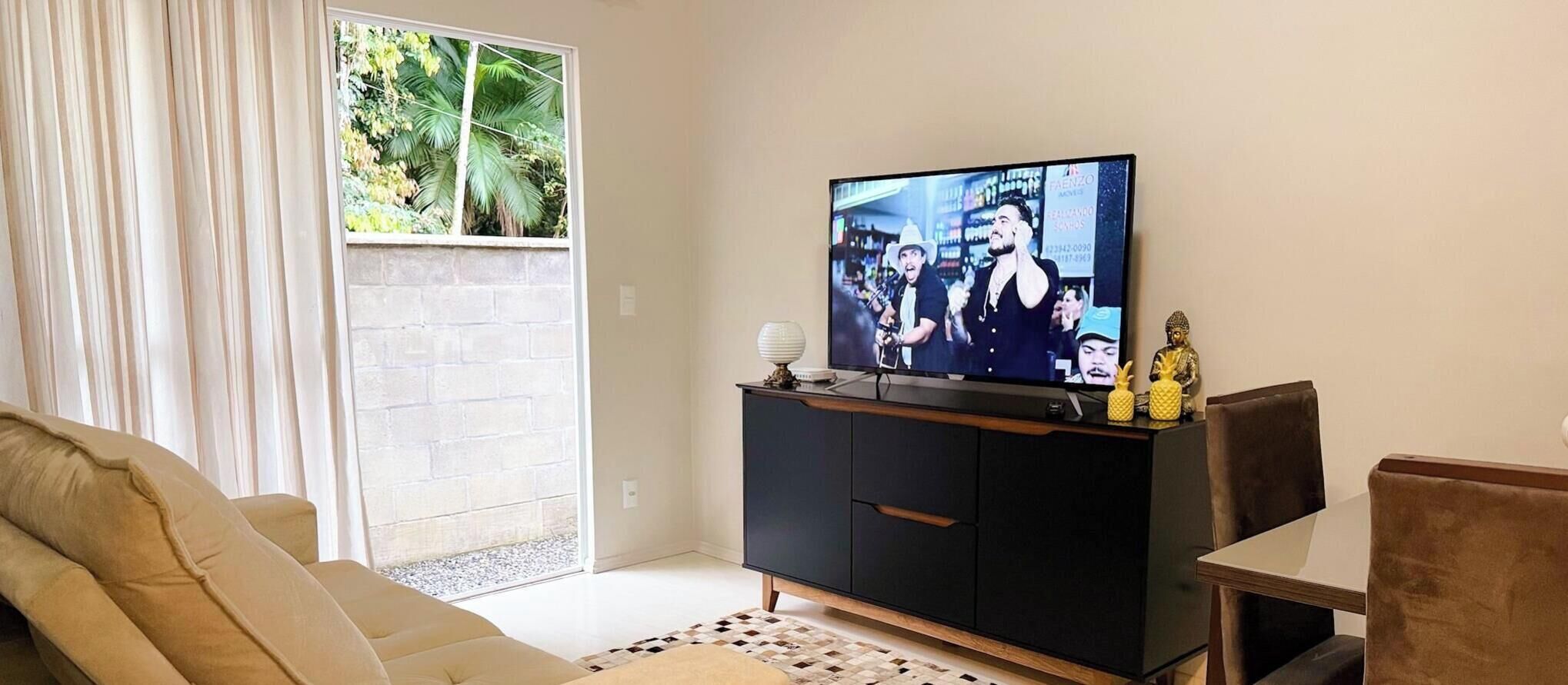 A living room with a television, a sofa, a coffee table, and a cabinet.